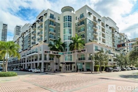 A large white building with a curved corner and a balcony on the top floor.
