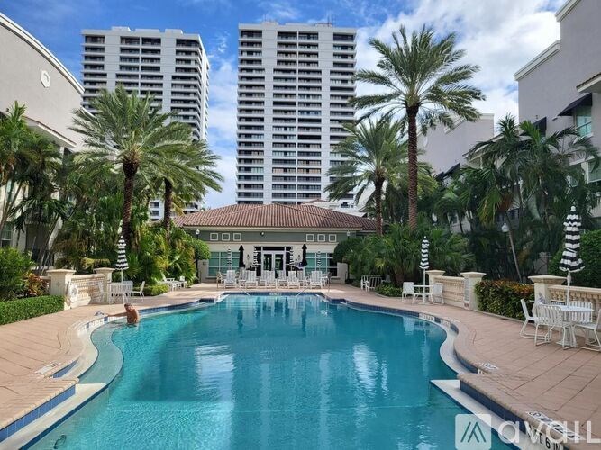 A swimming pool surrounded by palm trees and lounge chairs.