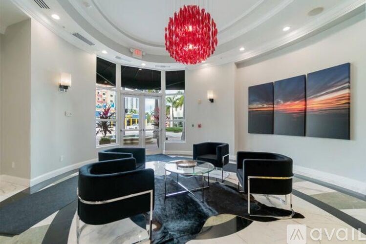 A living room with a red chandelier and black furniture.