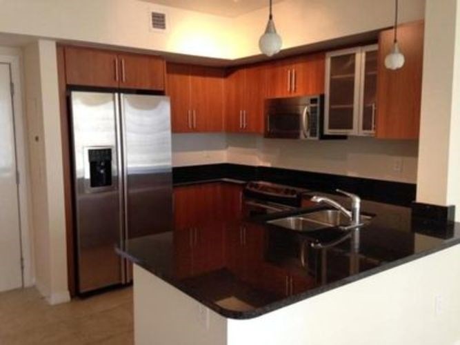 A kitchen with a black counter top and stainless steel appliances.