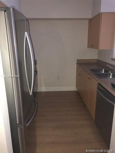A kitchen with a refrigerator and a sink.