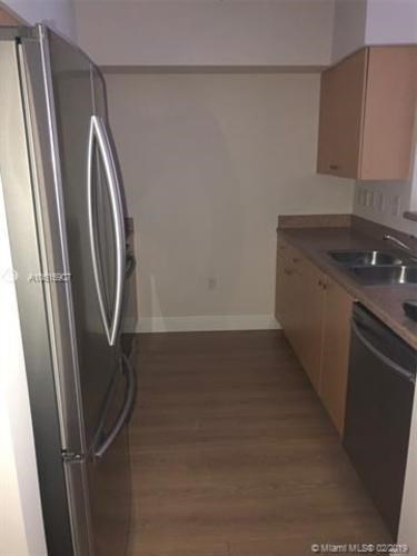 A kitchen with a refrigerator and a sink.