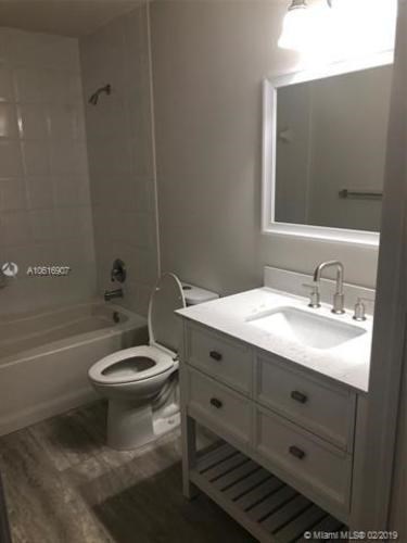 A white bathroom with a toilet, sink, and mirror.