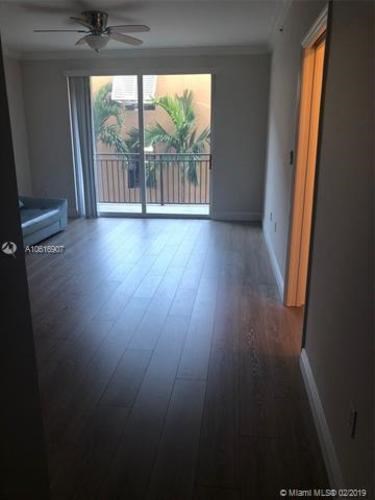 A room with a sliding glass door leading to a balcony with plants on it.