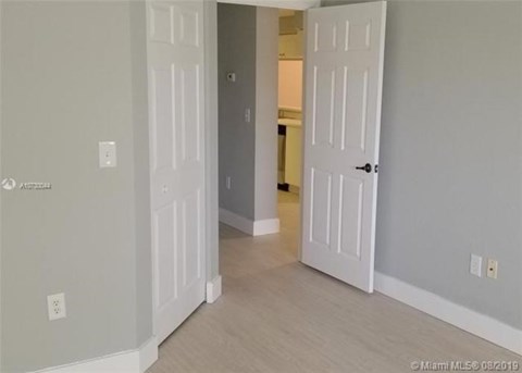 A room with two white doors and a light switch on the wall.