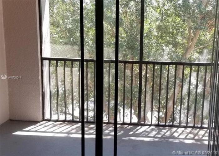A balcony with a metal railing and a view of trees outside.