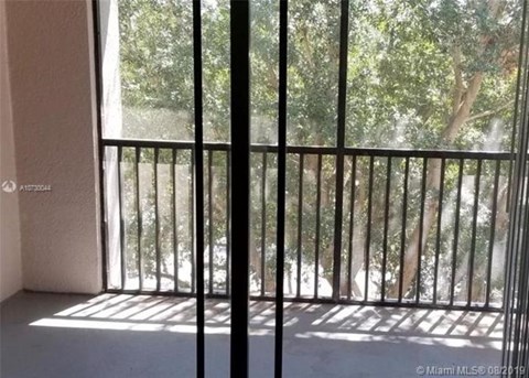 A balcony with a metal railing and a view of trees outside.