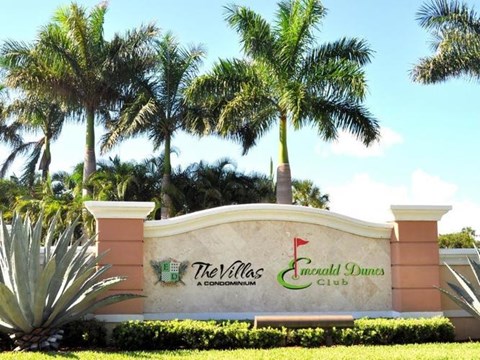 The Villas at Emerald Dunes Club sign with palm trees in the background.