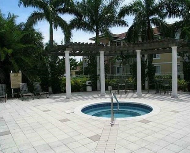 A pool surrounded by a white tile floor and a white pergola.
