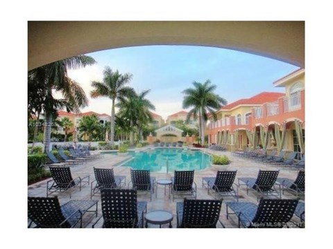 A pool surrounded by chairs and palm trees.