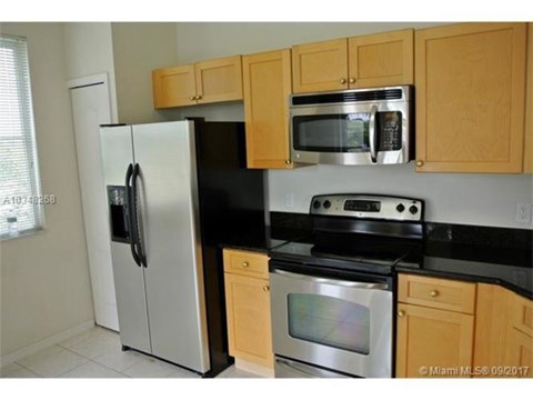 A kitchen with a stainless steel refrigerator, microwave, oven, and cabinets.