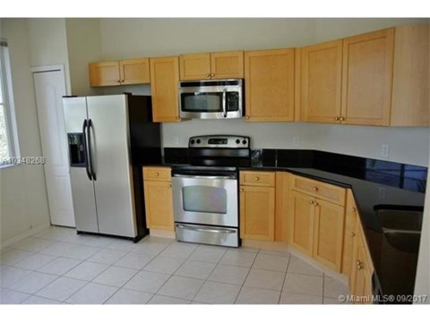 A kitchen with wooden cabinets and black countertops.