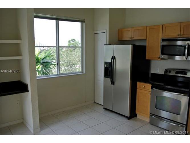 A kitchen with a refrigerator, microwave, and oven.