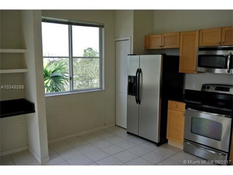 A kitchen with a refrigerator, microwave, and oven.
