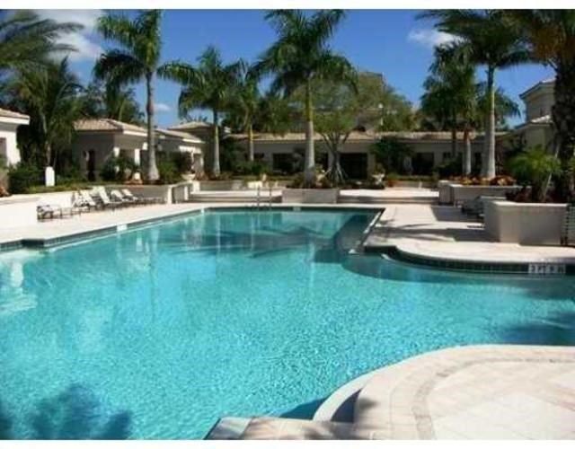 A swimming pool surrounded by palm trees and lounge chairs.