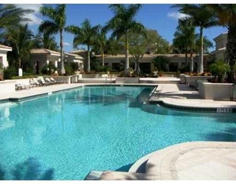 A swimming pool surrounded by palm trees and lounge chairs.