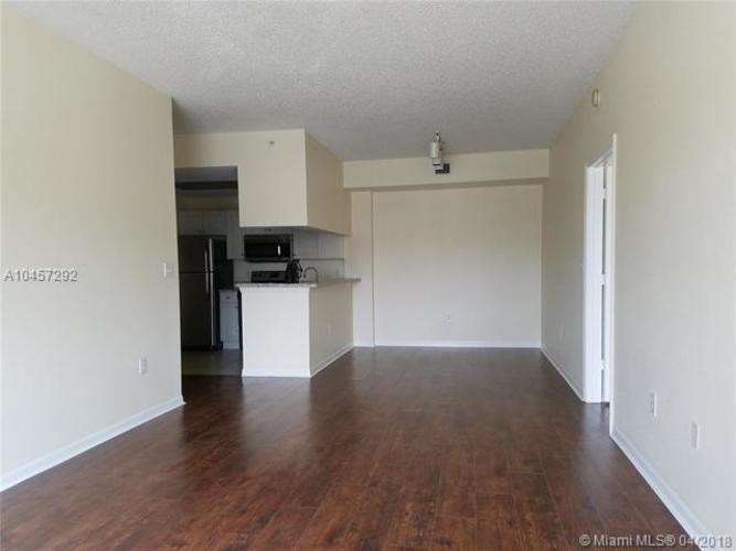 A spacious empty room with wood flooring and white walls.