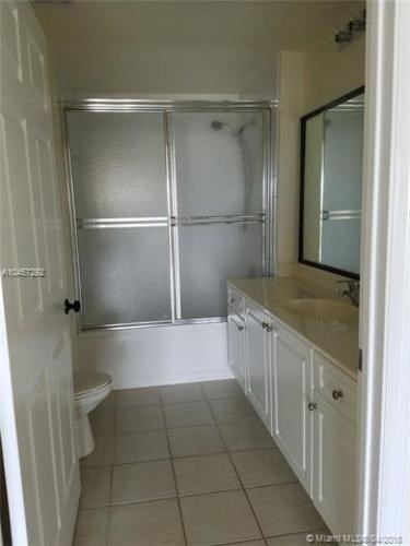 A white bathroom with a glass shower door and a white toilet.