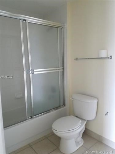 A white toilet in a small bathroom with a glass shower door.