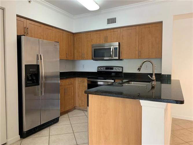 A kitchen with a black counter top and wooden cabinets.