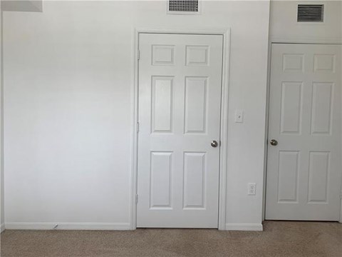A white door is in a room with a carpet floor.
