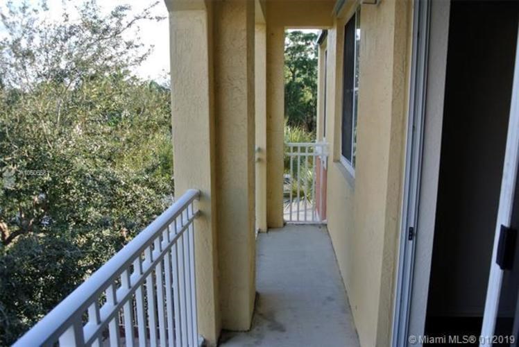 A balcony with a white railing and a view of trees.