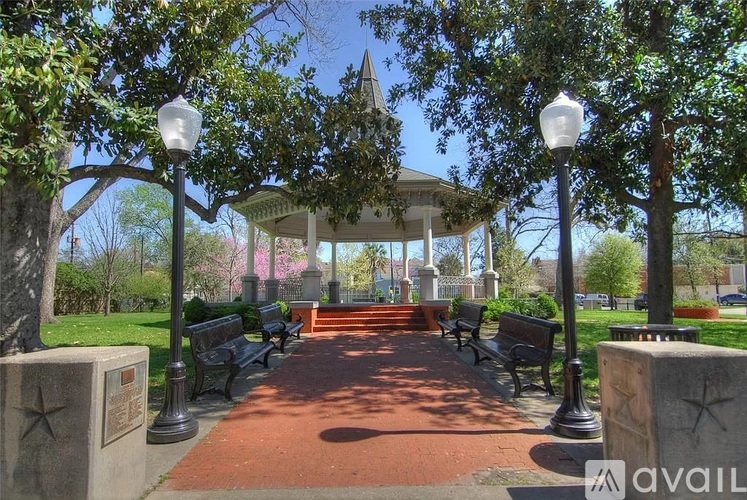 A gazebo is surrounded by benches and trees.