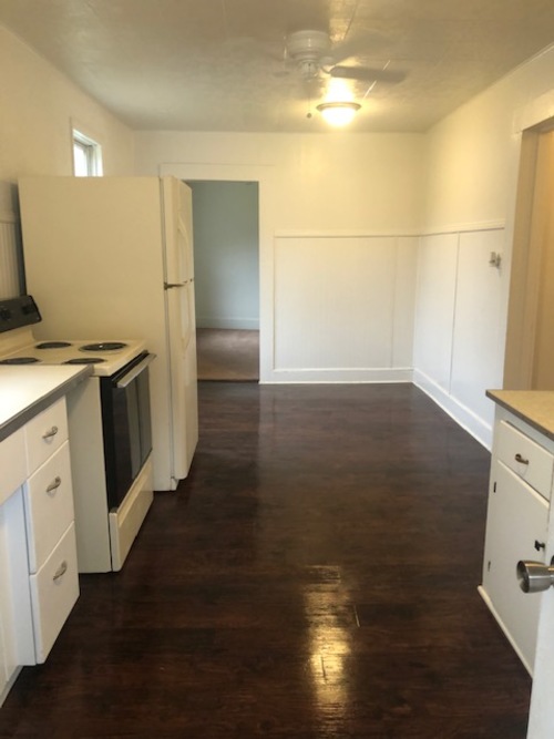A kitchen with white cabinets and a wooden floor.