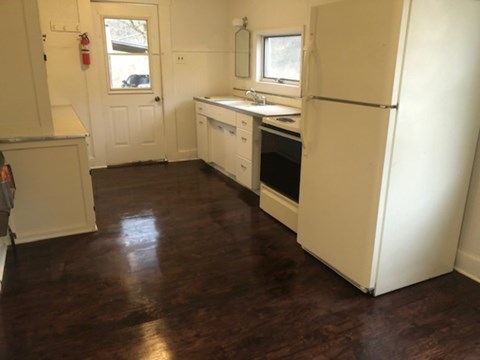 A kitchen with white appliances and wood floors.