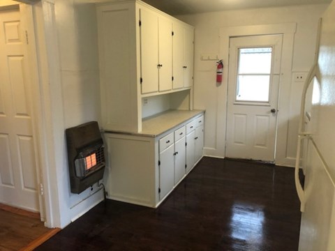 A white kitchen with a wood stove and cabinets.