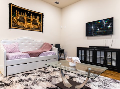 A living room with a white sofa and a television on the wall.