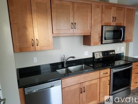A kitchen with wooden cabinets and black countertops.