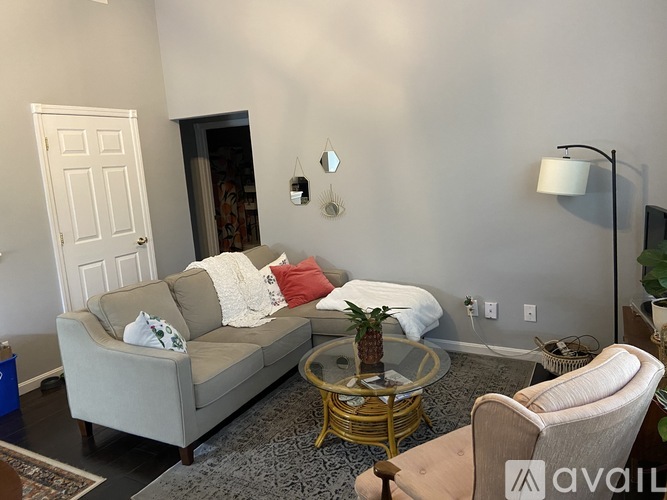 A living room with a grey couch, a white chair, and a coffee table.