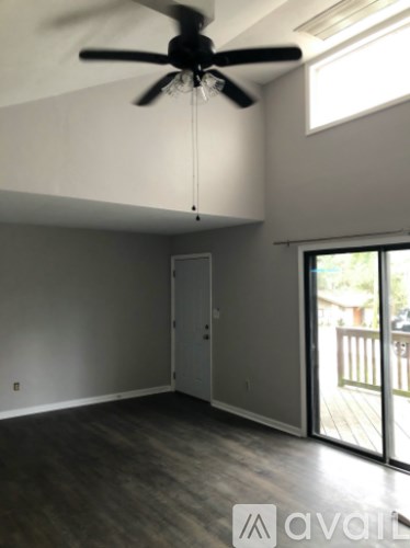 A room with a ceiling fan and sliding glass doors.