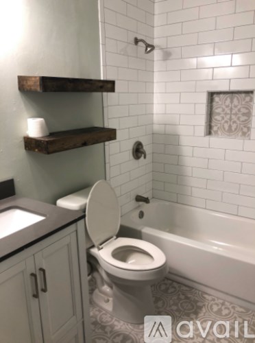 A white toilet in a bathroom with a white tiled wall.