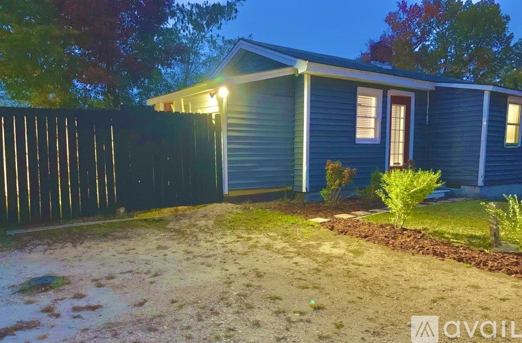 A blue house with a fence and a small garden in front.
