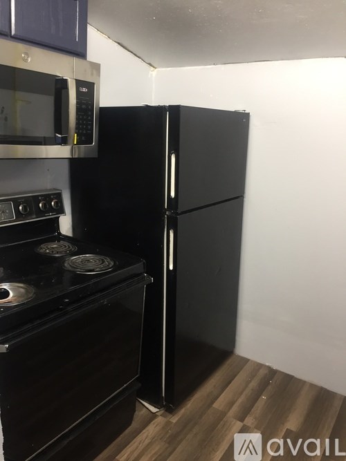 A black fridge and stove in a small kitchen.