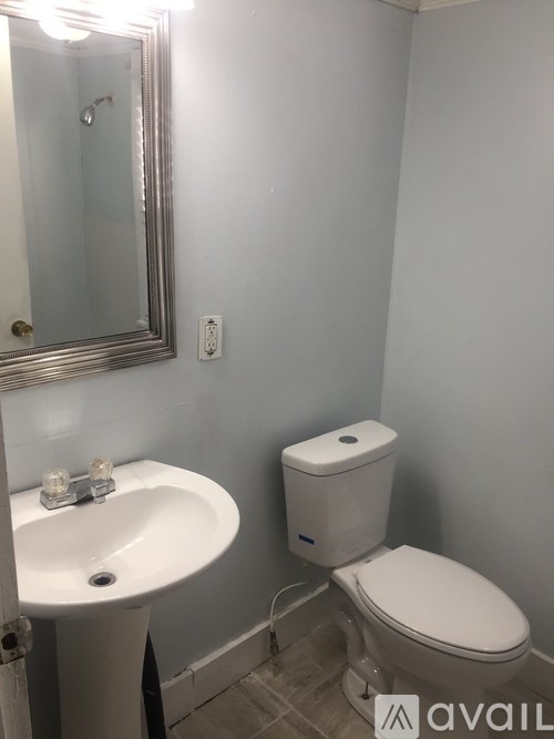 A bathroom with a toilet, sink, and mirror.