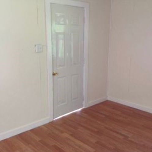 A white door is in a room with wooden flooring.