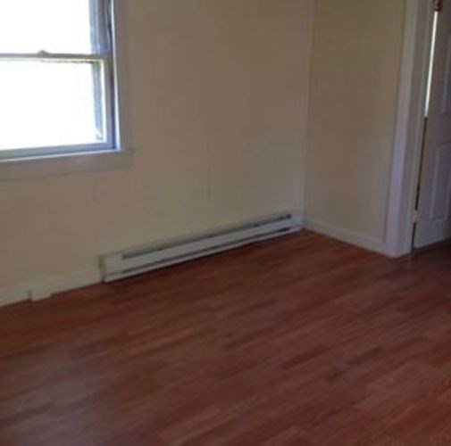 A room with a window and a radiator on the floor.