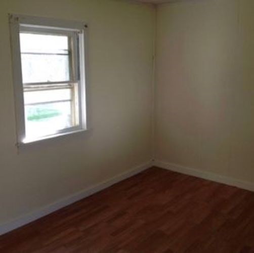 A room with a window and wooden flooring.