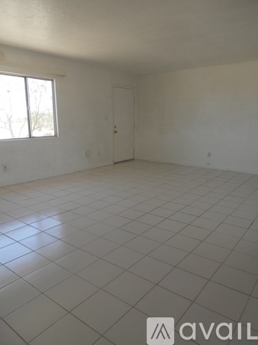 A large empty room with a tiled floor and a window.