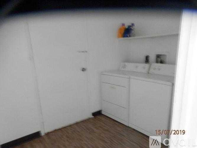 A white bathroom with a wooden floor and a white cabinet.