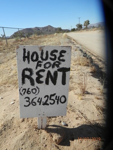 A sign in the desert advertises a house for rent.