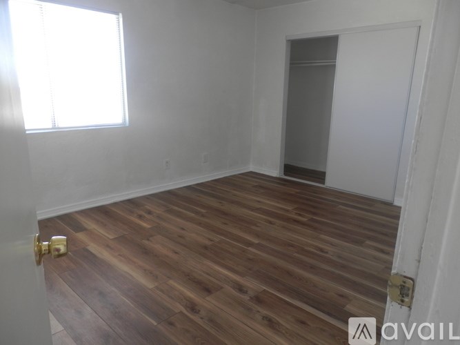 A room with wooden flooring and a door on the right side.