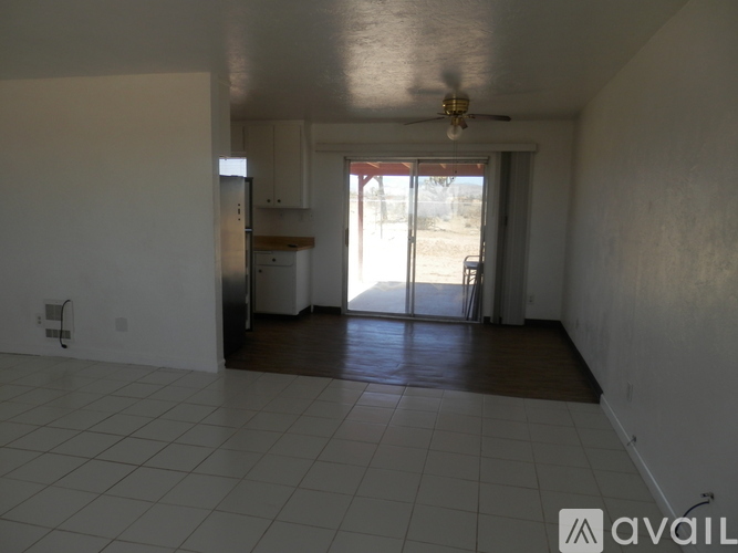 A spacious room with a ceiling fan and sliding glass doors leading to a backyard.