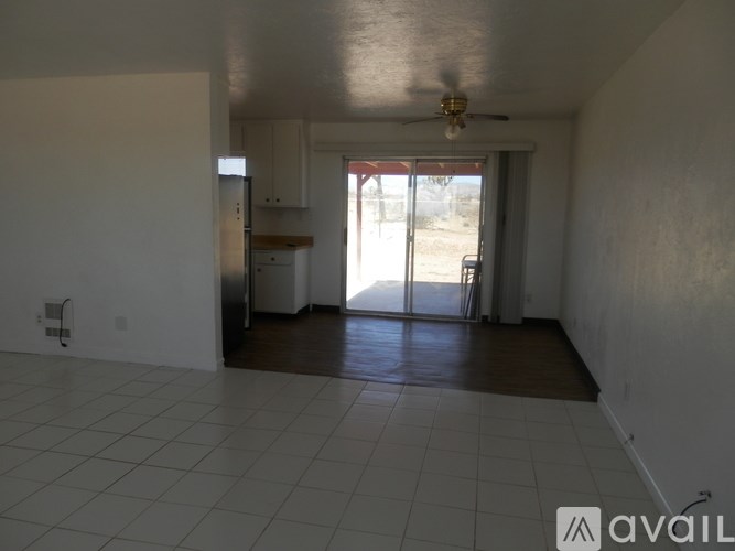A spacious room with a ceiling fan and sliding glass doors leading to a backyard.