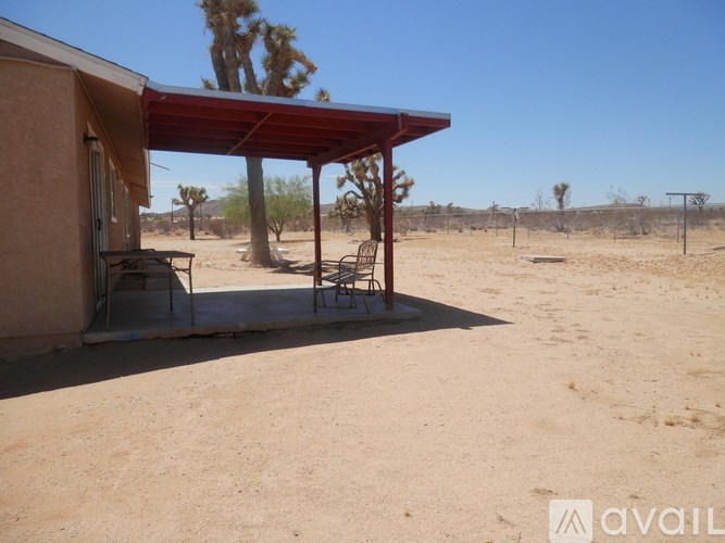 A house with a red roof and a covered patio area with chairs and a table.
