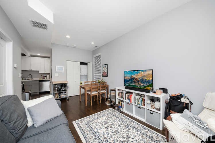 A living room with a grey couch and a painting on the wall.
