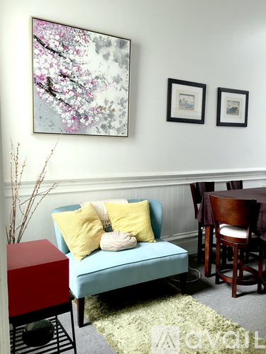 A living room with a blue couch and a red side table.